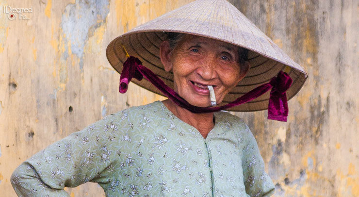 Happy, smiling old smoking woman in conical hat - vietnam